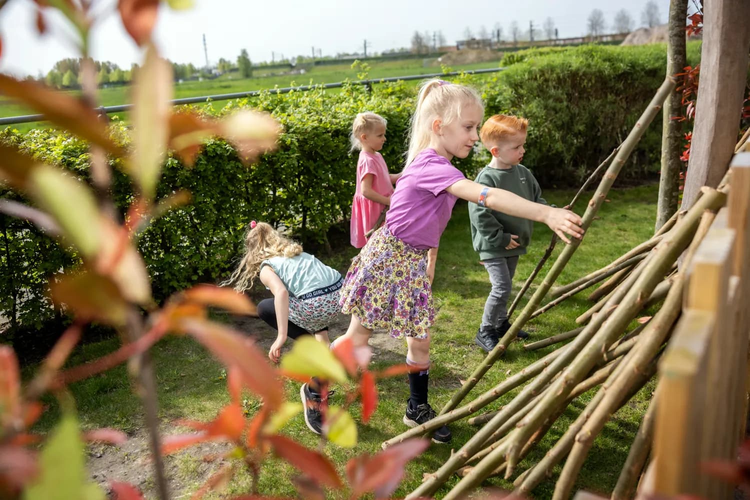 Kinderen bouwen een hut van takken bij kinderopvang Kind&co ludens