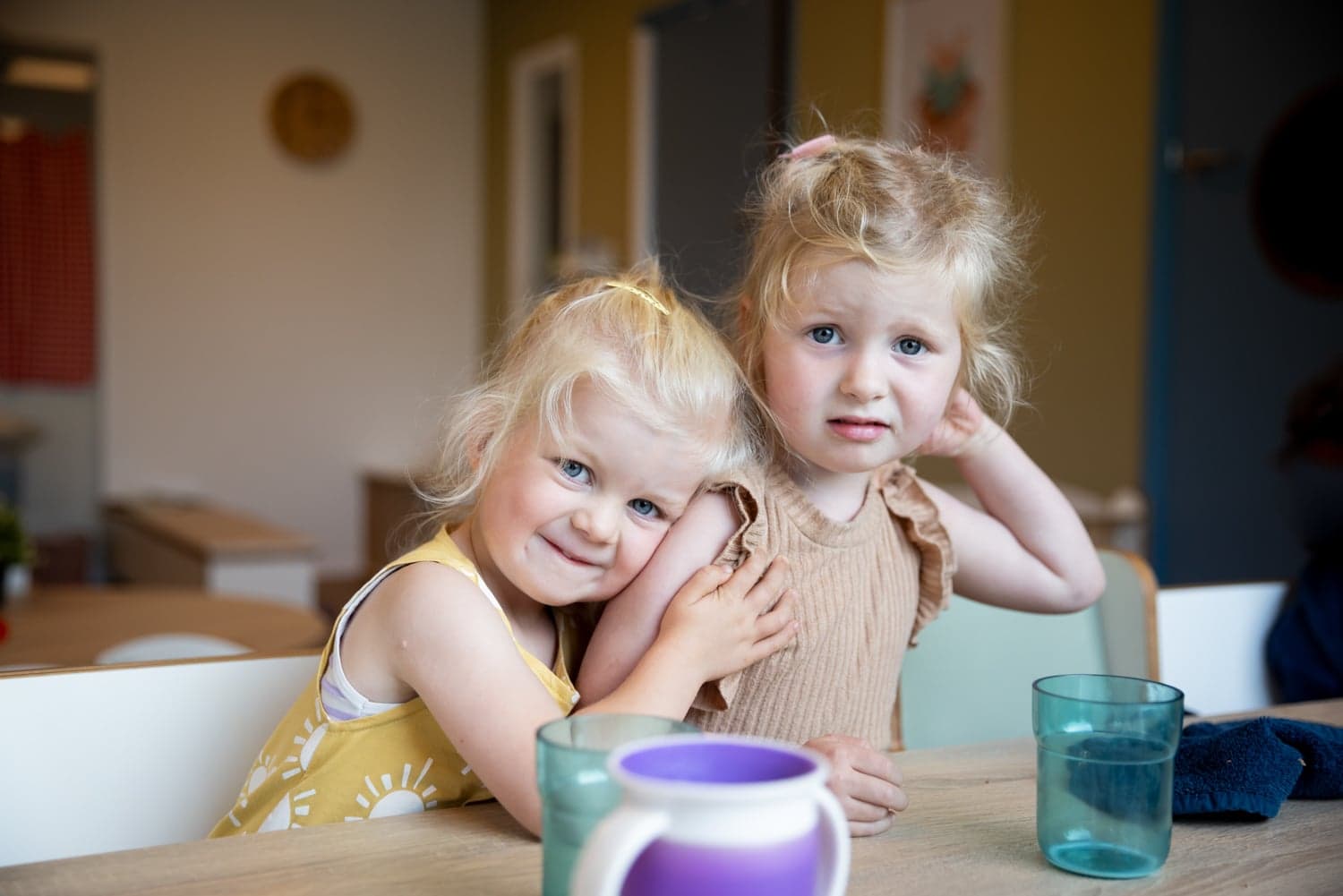 Kinderen knuffelen elkaar aan bij tafel bij kinderopvang Kind&co ludens