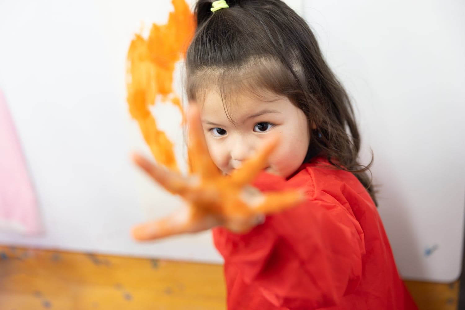 Blij kind verft met haar handen bij kinderopvang Kind&co ludens