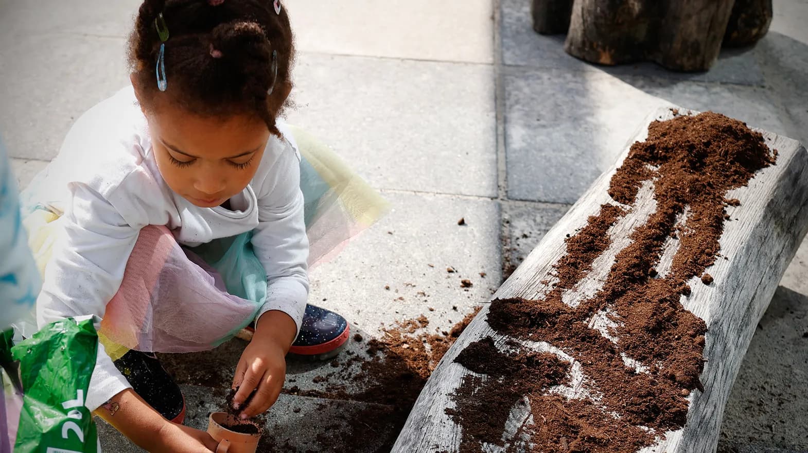 Kind van de peutergroep poot zaadjes in de moestuin bij kinderopvang Kind&co ludens