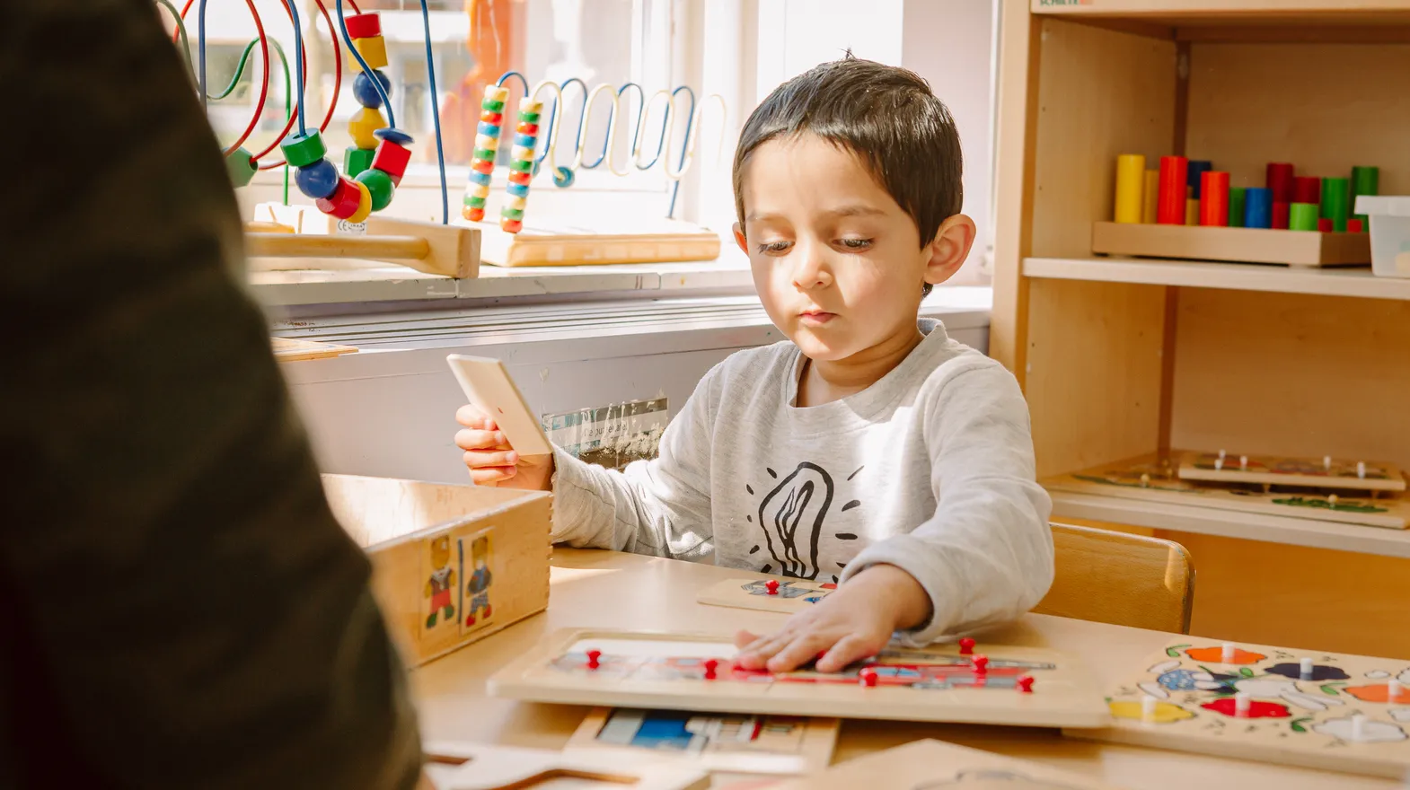 Kind maakt legpuzzels aan tafel bij peuteropvang De Kleine Wijzer, kinderopvang Kind&co ludens