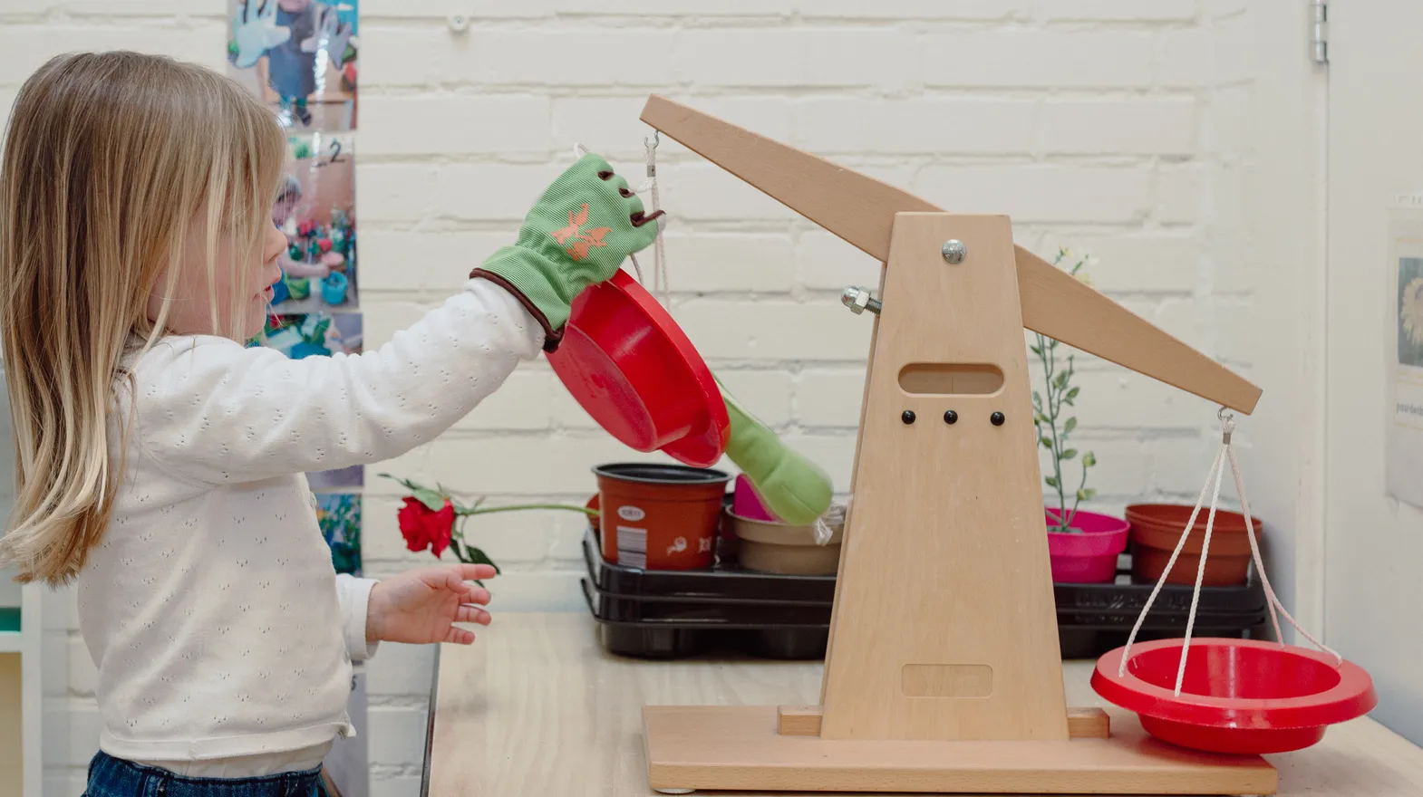 Een kind van de peutergroep speelt met een weegschaal bij kinderopvang Kind&co ludens