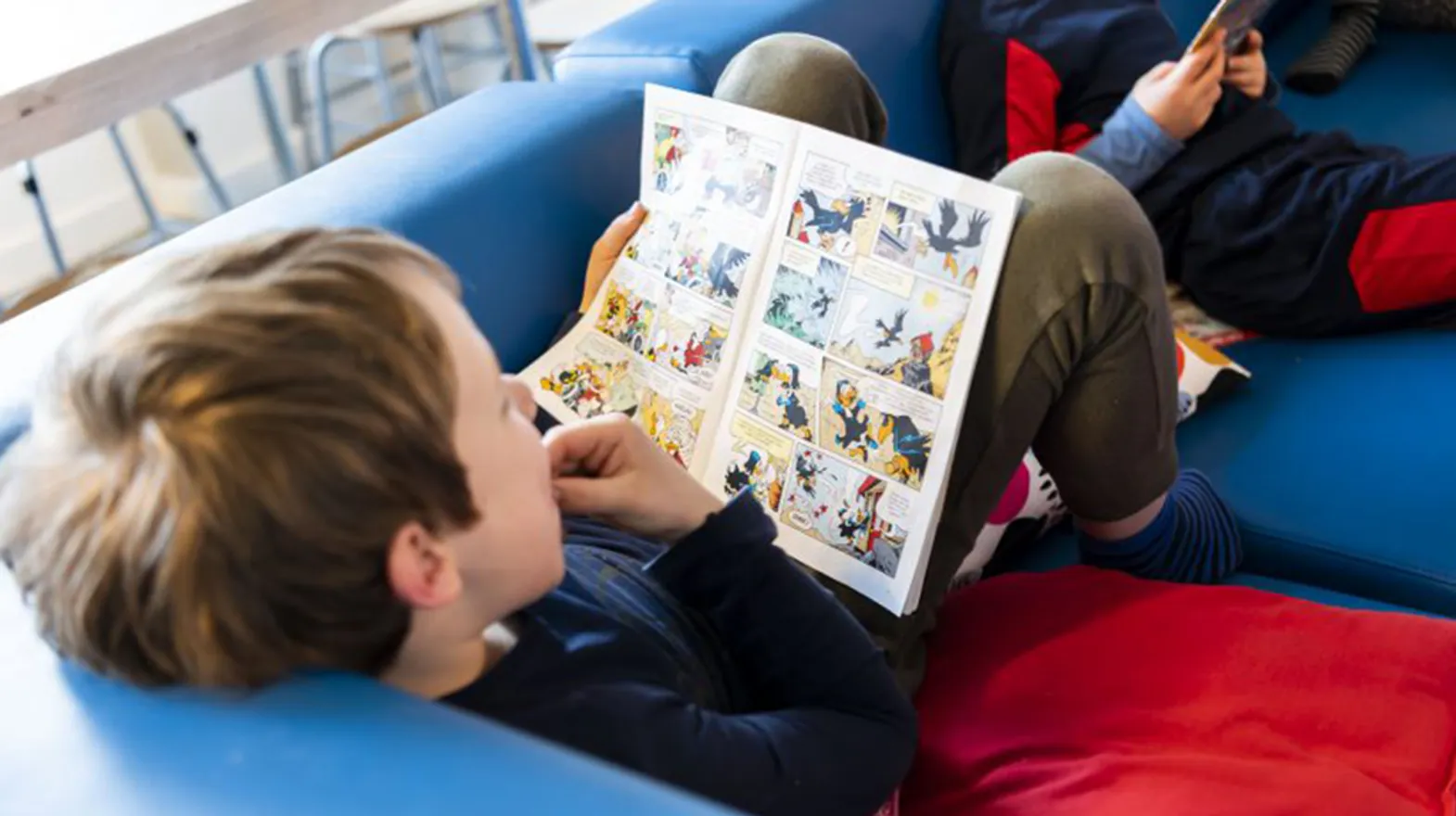 Kind lezend op de bank bij BSO De Wilde Poema Bilthoven van kinderopvang Kind&co ludens
