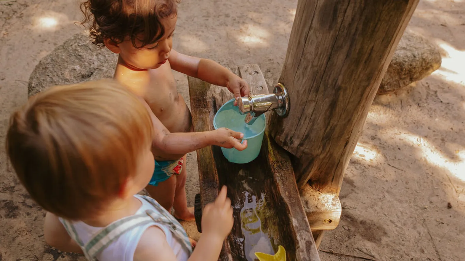 Kinderen spelen buiten met modder en water bij kinderopvang Kind&co ludens