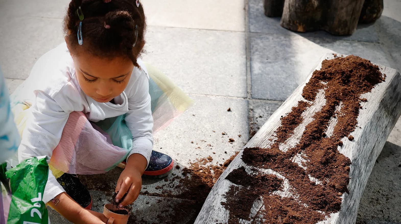 Kind van de peutergroep poot zaadjes in de moestuin bij kinderopvang Kind&co ludens