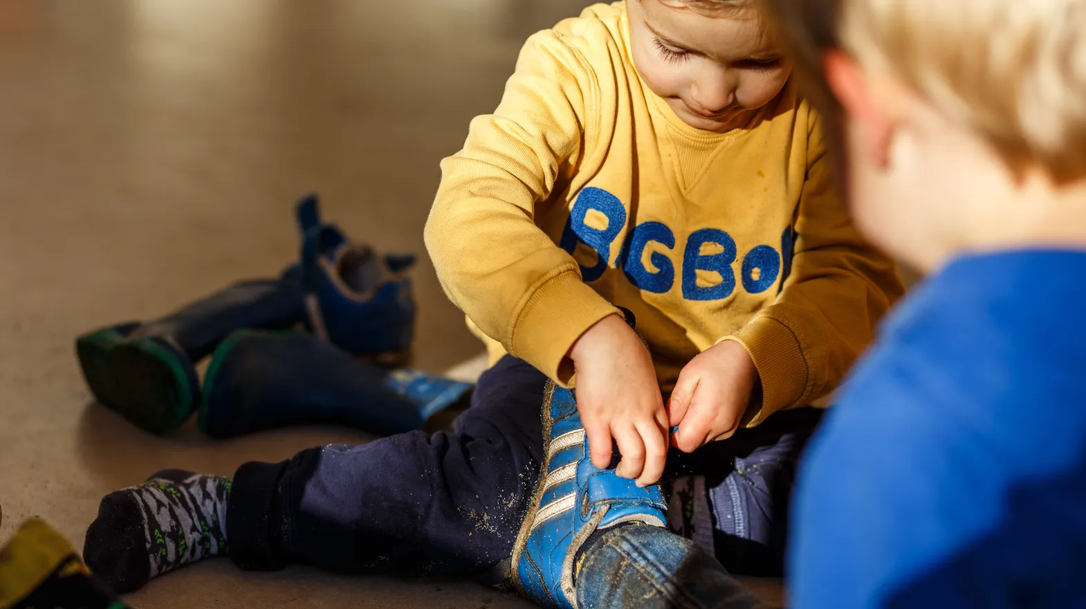 Kinderen doen samen hun schoenen uit bij kinderopvang Kind&co ludens