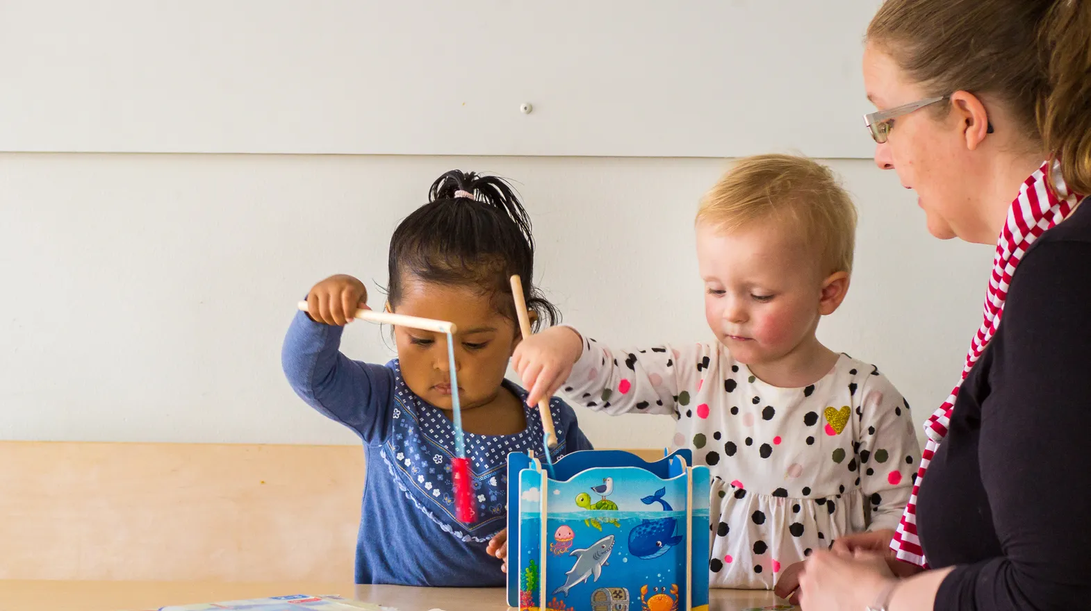 Kinderen spelen samen "Vissen" onder begeleiding van een pedagogisch medewerker bij kinderopvang Kind&co ludens