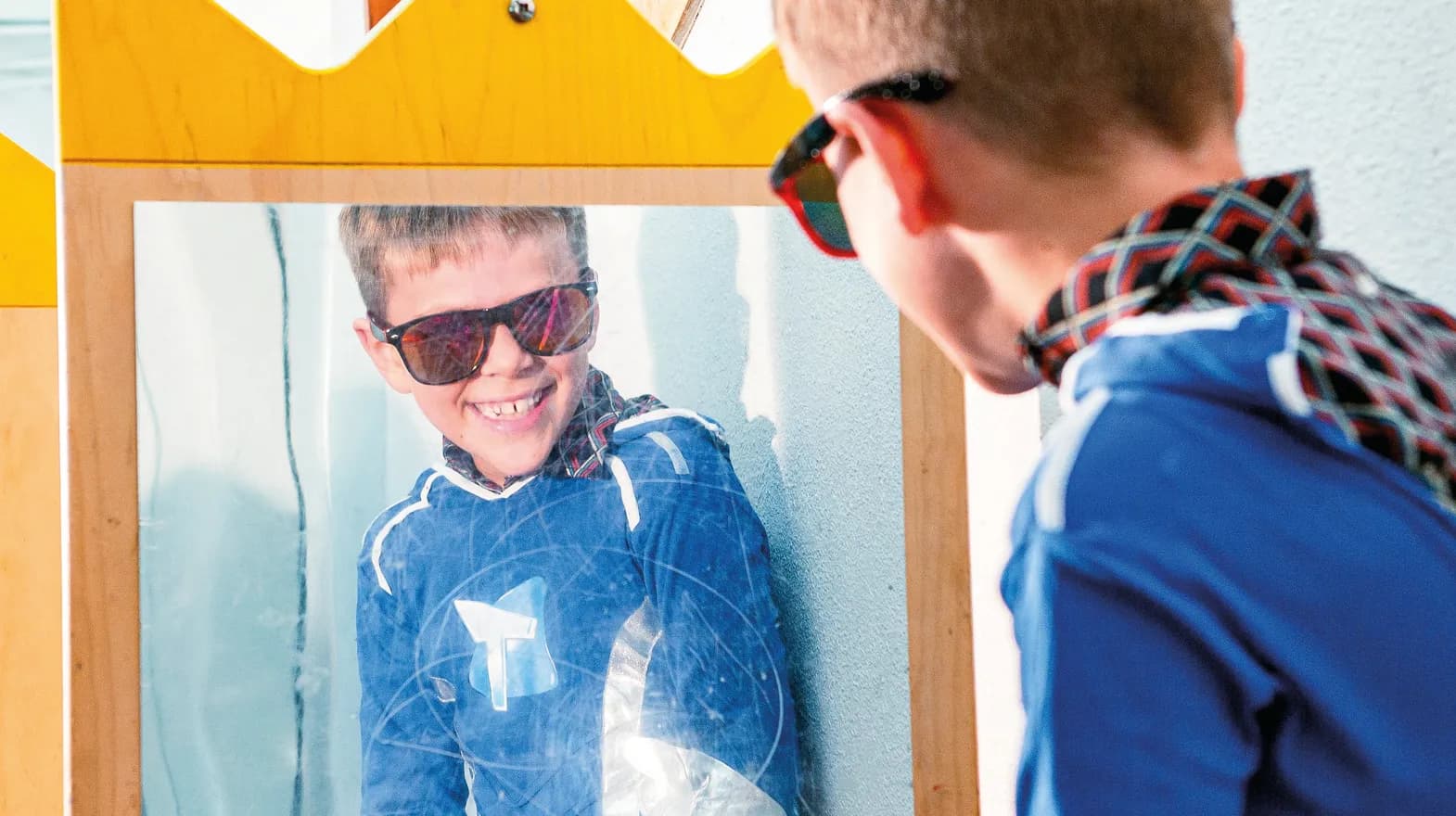 Kind op de BSO heeft veel plezier tijdens een verkleedpartij bij het kijken in de spiegel van kinderopvang Kind&co ludens