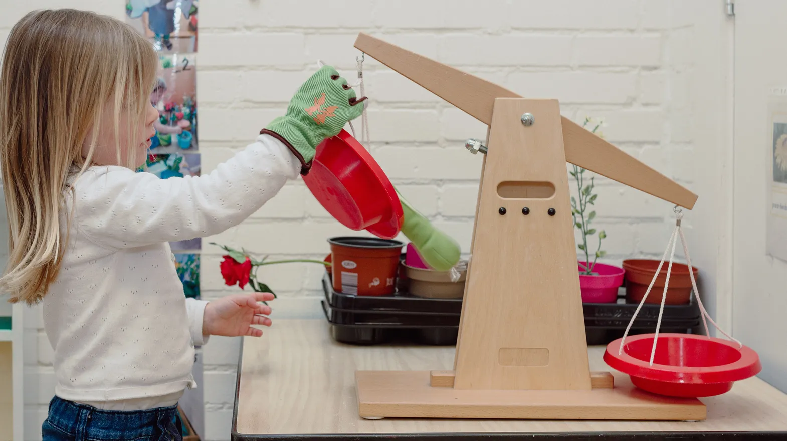 Een kind van de peutergroep speelt met een weegschaal bij kinderopvang Kind&co ludens