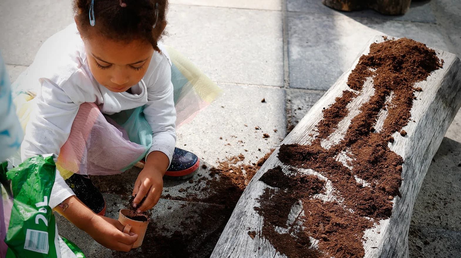 Kind van de peutergroep poot zaadjes in de moestuin bij kinderopvang Kind&co ludens