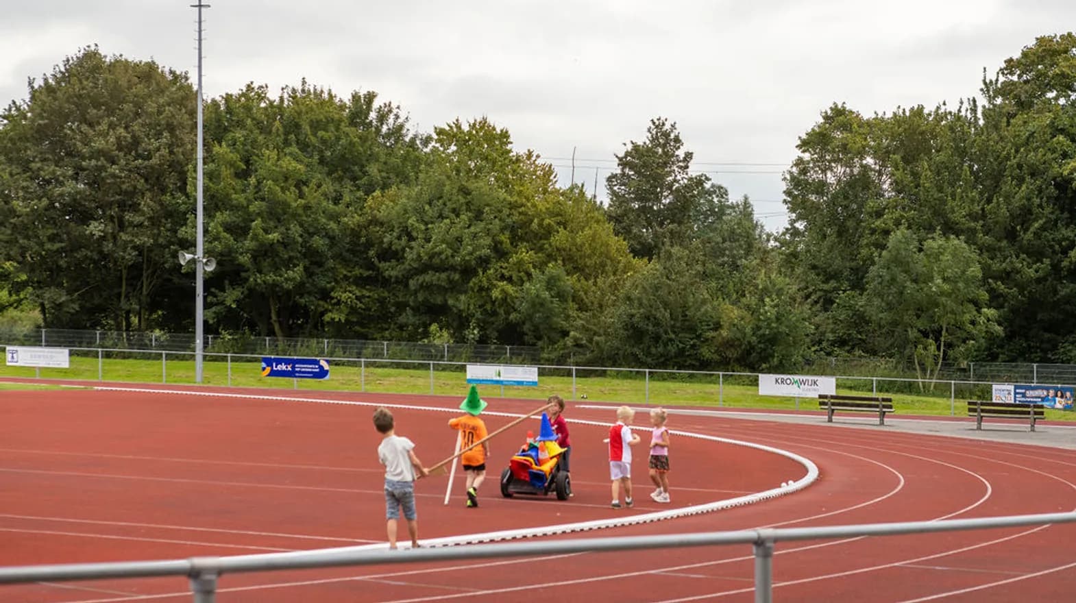 Kinderen verzamelen pionnen op de atletiekbaan van buitenschoolse opvang Asterix en Obelix, kinderopvang Kind&co Ludens