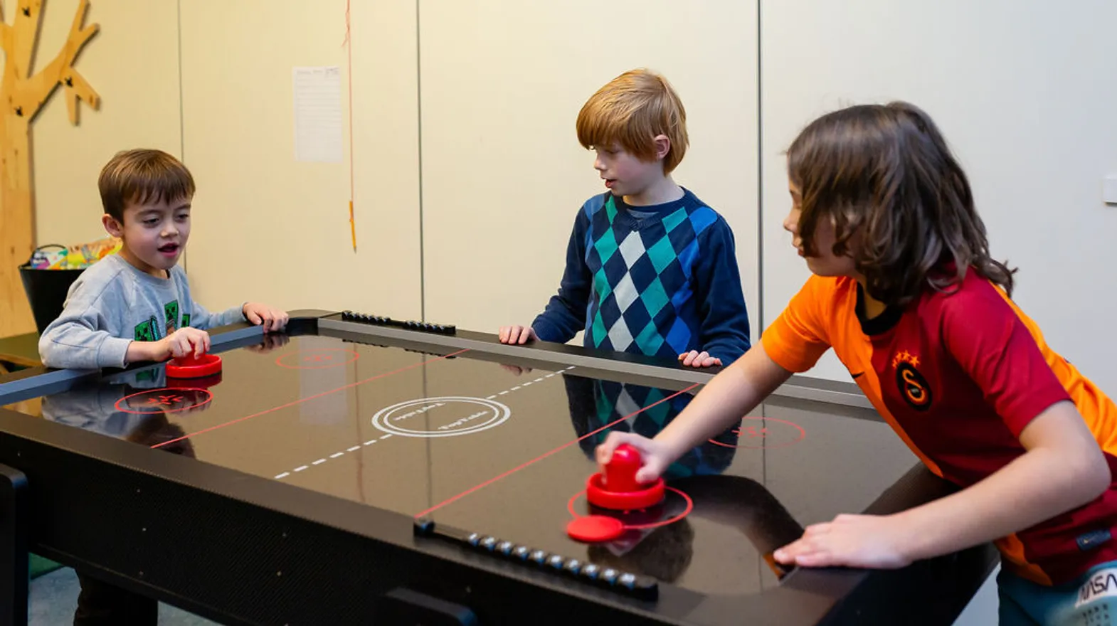 Kinderen spelen airhockey met elkaar bij BSO Villa Kinderkeet van kinderopvang Kind&co Ludens