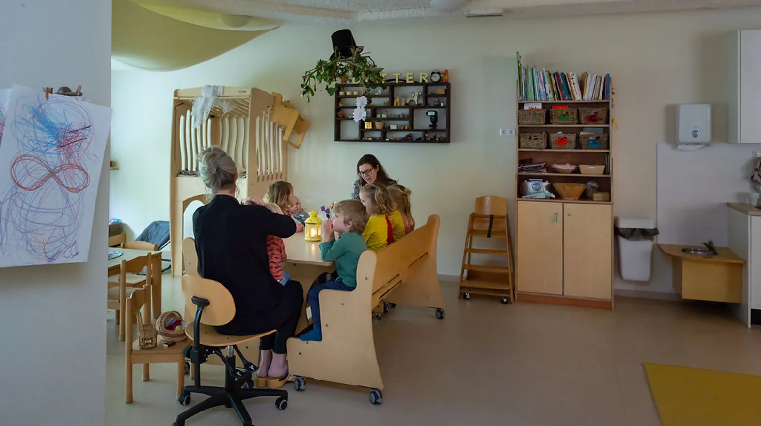 Kinderen zitten aan tafel en luisteren naar een boek bij kinderdagverblijf Rozenrood, kinderopvang Kind&co ludens