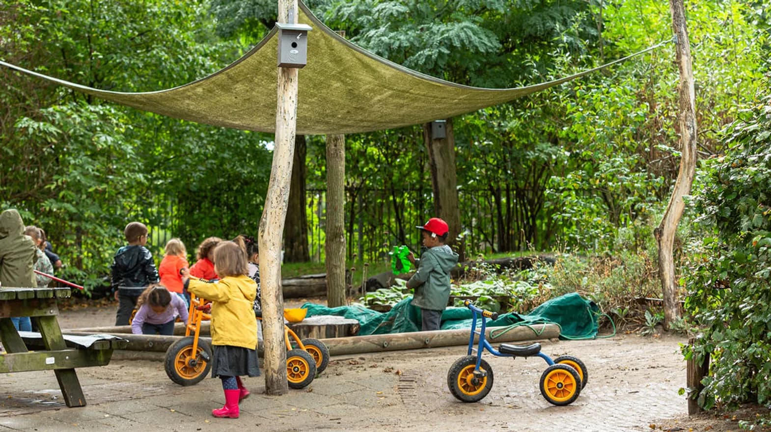 Kinderen spelen buiten met fietsjes en in de zandbak bij kinderdagverblijf Hummeltje, Kind&co ludens