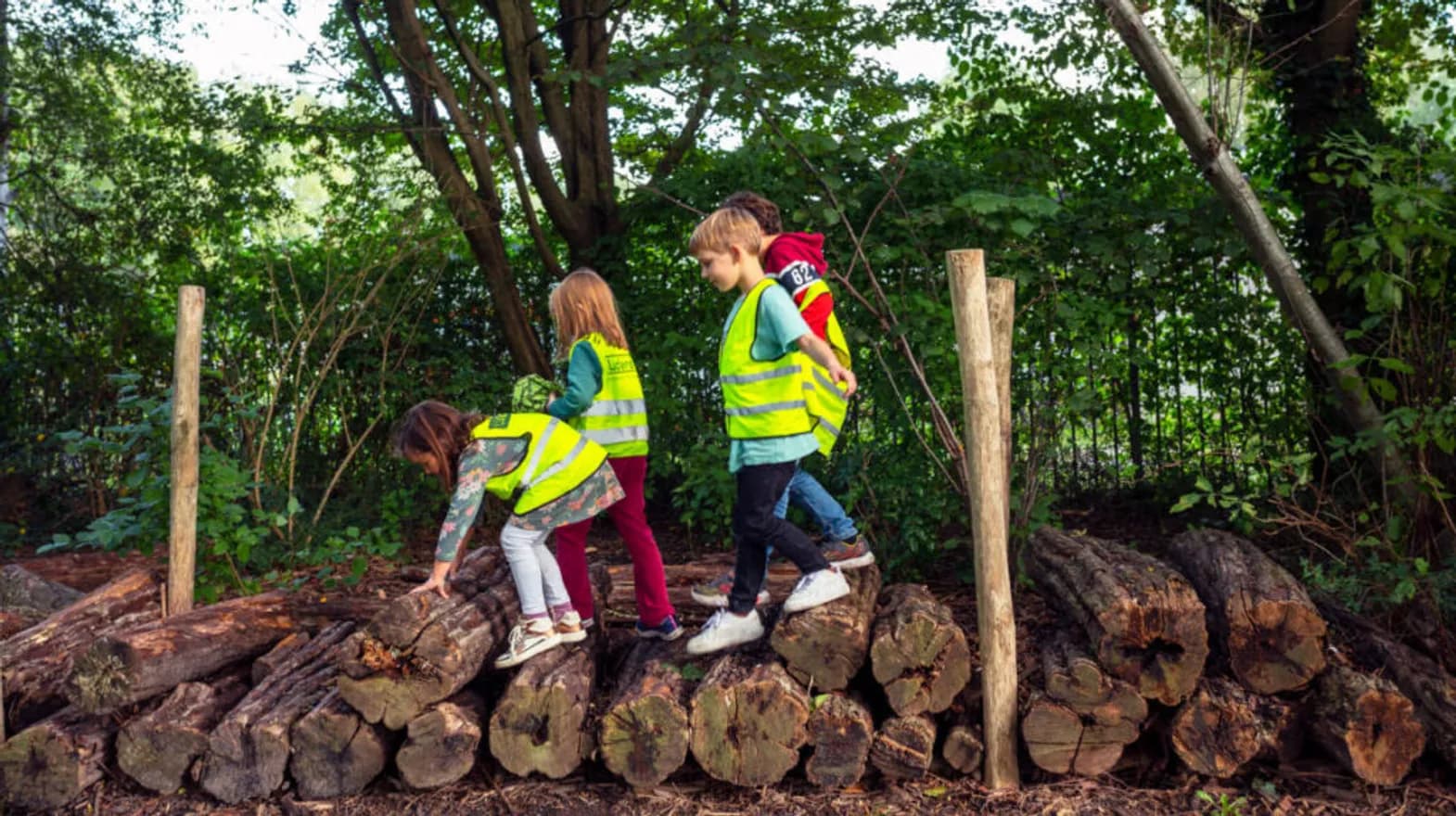 Kinderen lopen over boomstronken bij buitenschoolse opvang Rijnridders van kinderopvang Kind&co Ludens