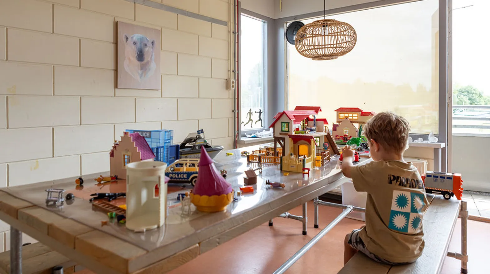 Kind speelt met playmobilhuis aan grote tafel bij buitenschoolse opvang Asterix en Obelix, kinderopvang Kind&co Ludens
