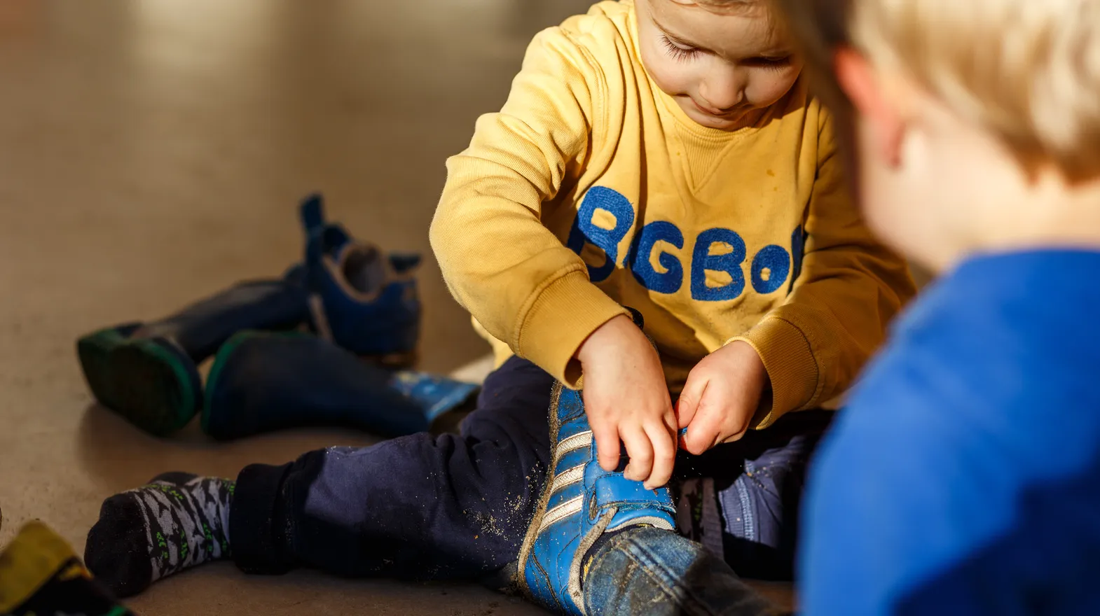 Kinderen doen samen hun schoenen uit bij kinderopvang Kind&co ludens