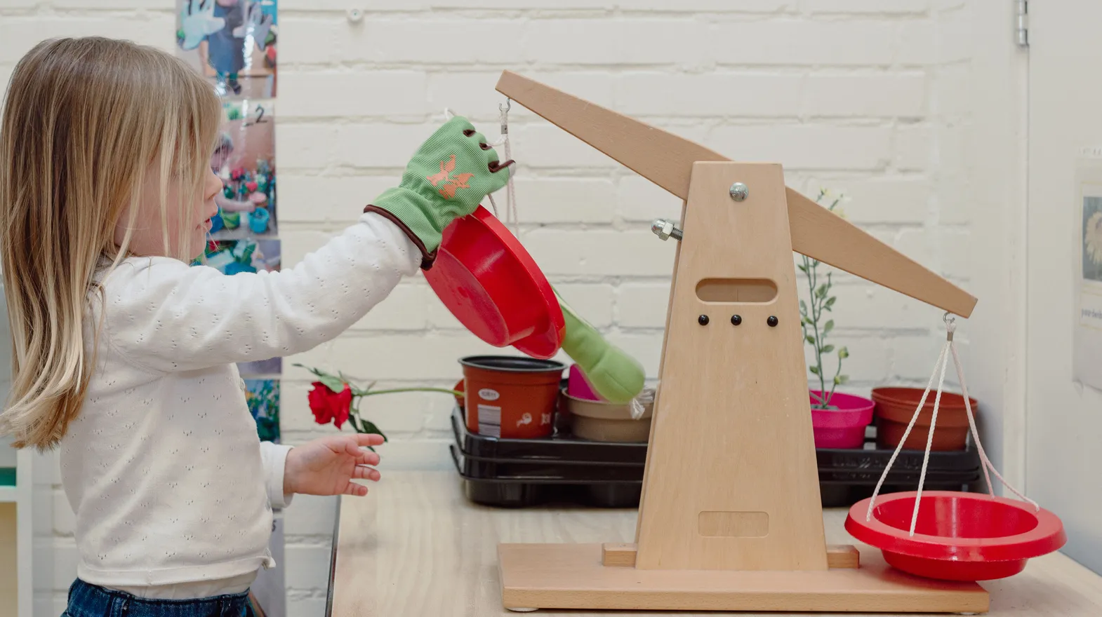 Een kind van de peutergroep speelt met een weegschaal bij kinderopvang Kind&co ludens