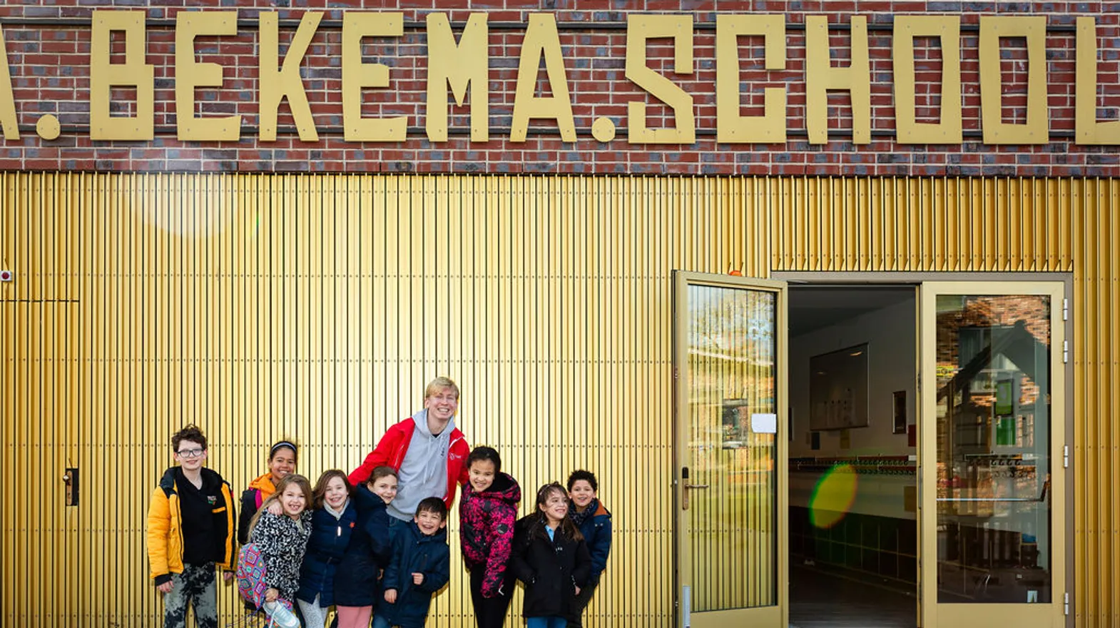 Kinderen staan lachend voor het pand van buitenschoolse opvang Villa Bekema, kinderopvang Kind&co Ludens