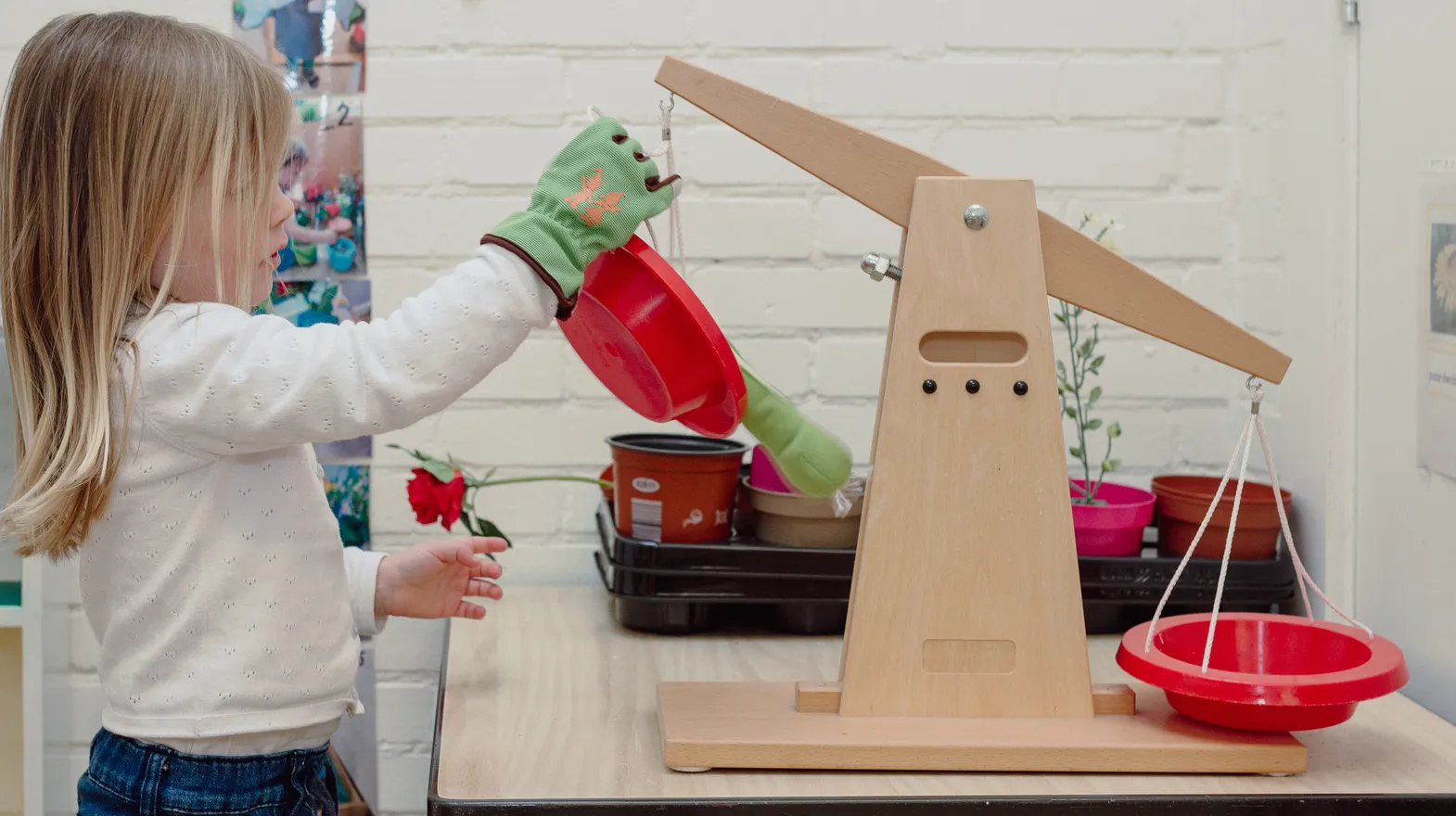 Een kind van de peutergroep speelt met een weegschaal bij kinderopvang Kind&co ludens