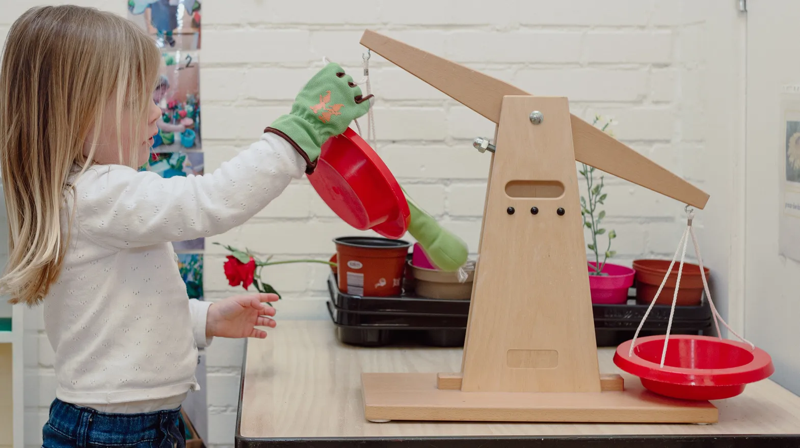 Een kind van de peutergroep speelt met een weegschaal bij kinderopvang Kind&co ludens