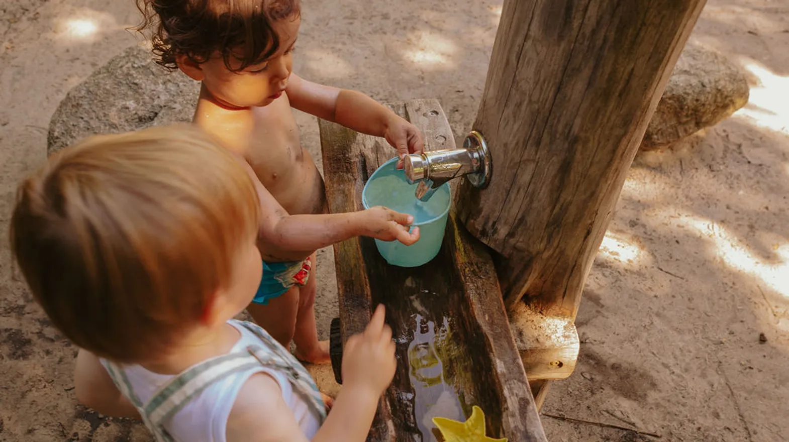 Kinderen spelen buiten met modder en water bij kinderopvang Kind&co ludens