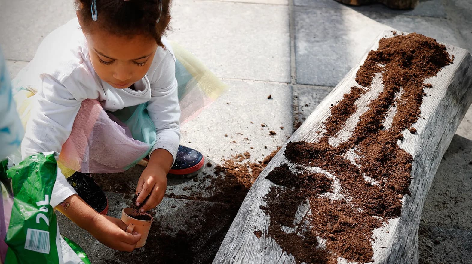Kind van de peutergroep poot zaadjes in de moestuin bij kinderopvang Kind&co ludens