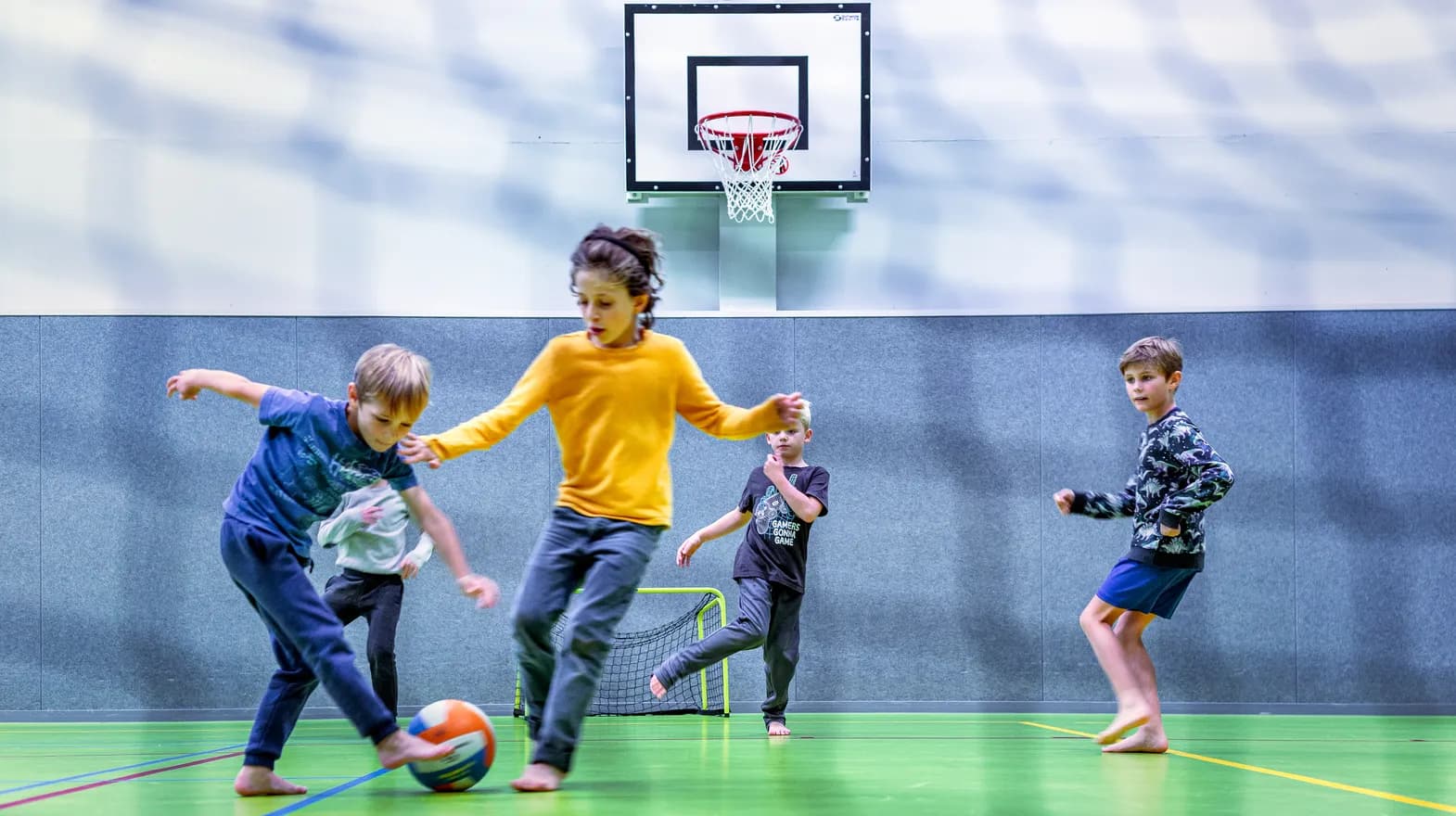 Kinderen van de BSO spelen samen voetbal in de gymzaal bij kinderopvang Kind&co ludens