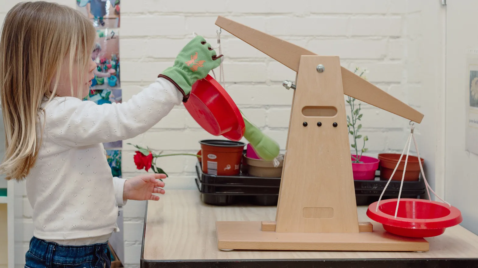 Een kind van de peutergroep speelt met een weegschaal bij kinderopvang Kind&co ludens