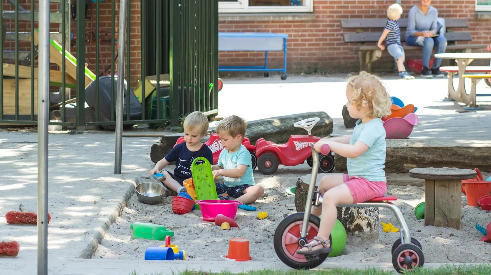 Kinderen fietsen buiten op het speelplein bij kinderdagverblijf Jodokus, kinderopvang Kind&co ludens