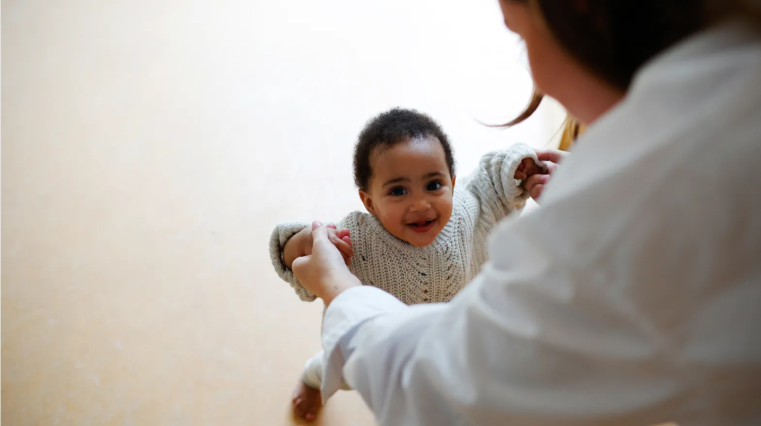 Peuter leert stapjes lopen met pedagogisch medewerker bij kinderopvang Kind&co ludens