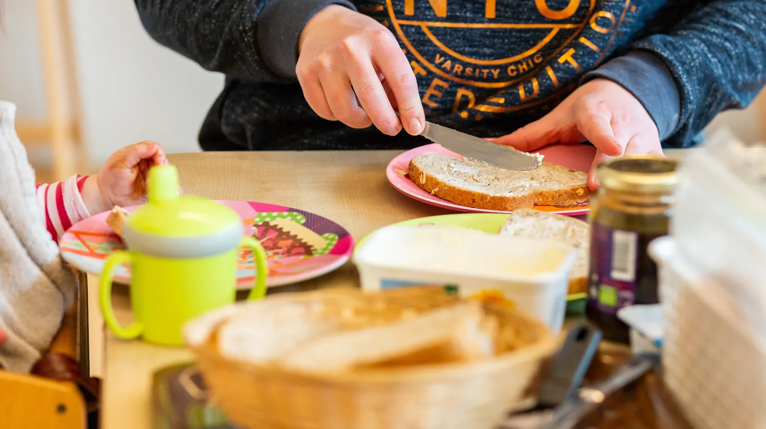 Pedagogisch medewerker smeert een boterham voor de kinderen bij kinderdagverblijf Het Palet, kinderopvang Kind&co ludens