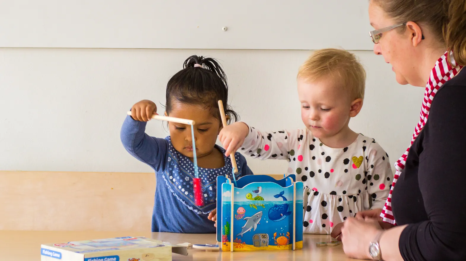 Kinderen spelen samen "Vissen" onder begeleiding van een pedagogisch medewerker bij kinderopvang Kind&co ludens
