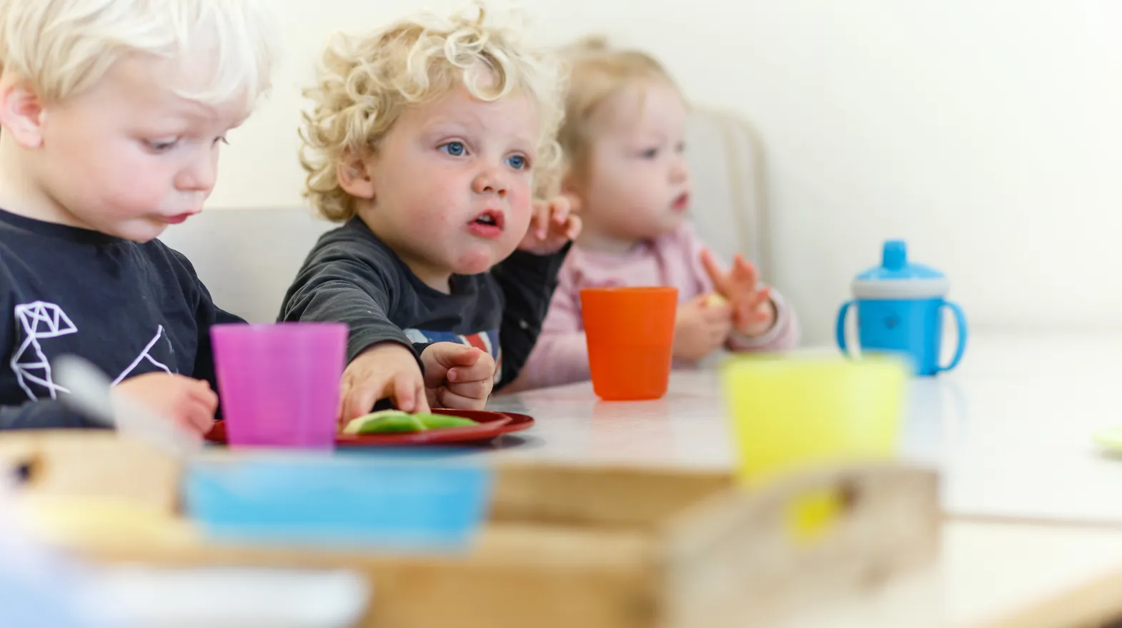 Kinderen eten fruit aan tafel bij kinderdagverblijf Harlekijn, kinderopvang Kind&co ludens