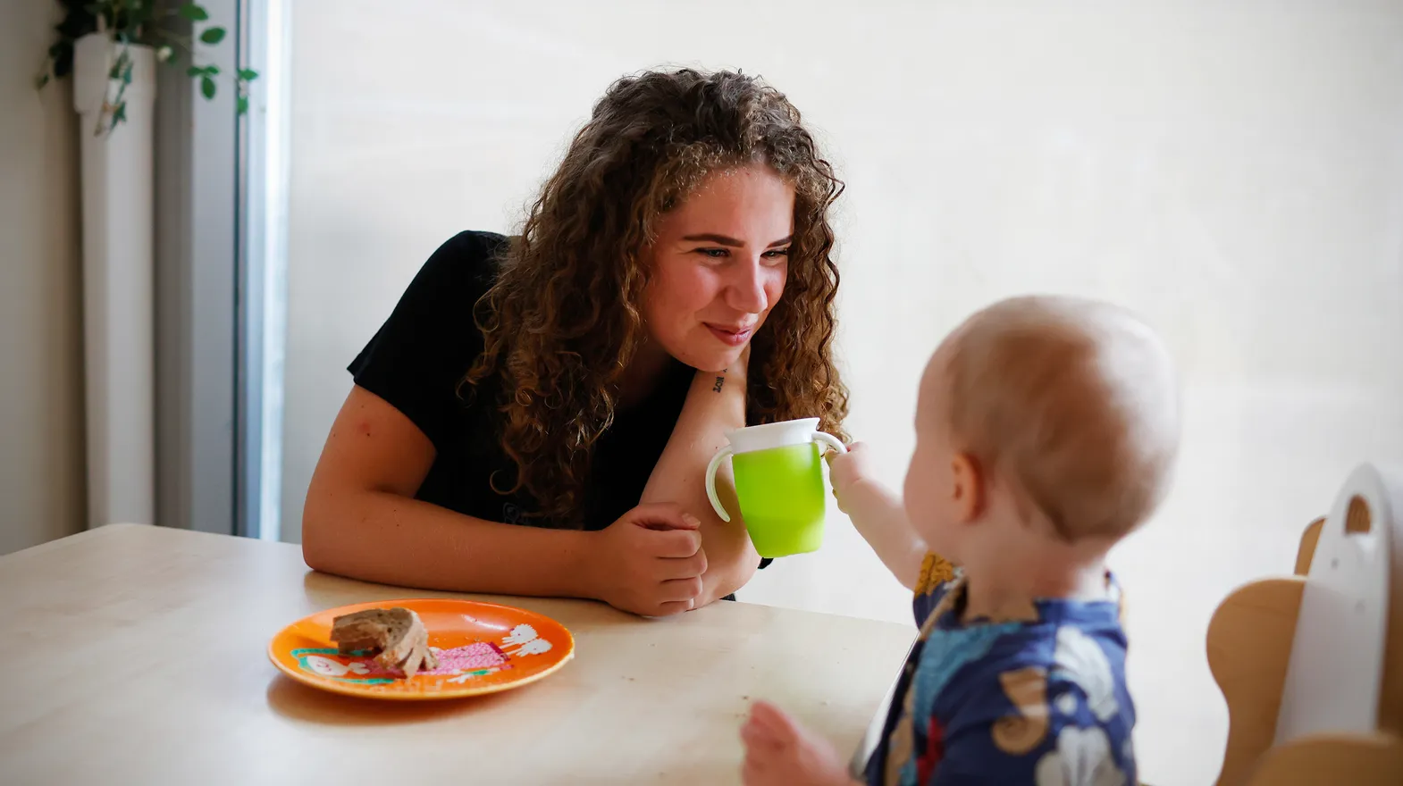 Kind eet samen met pedagogisch medewerker bij kinderopvang Kind&co ludens