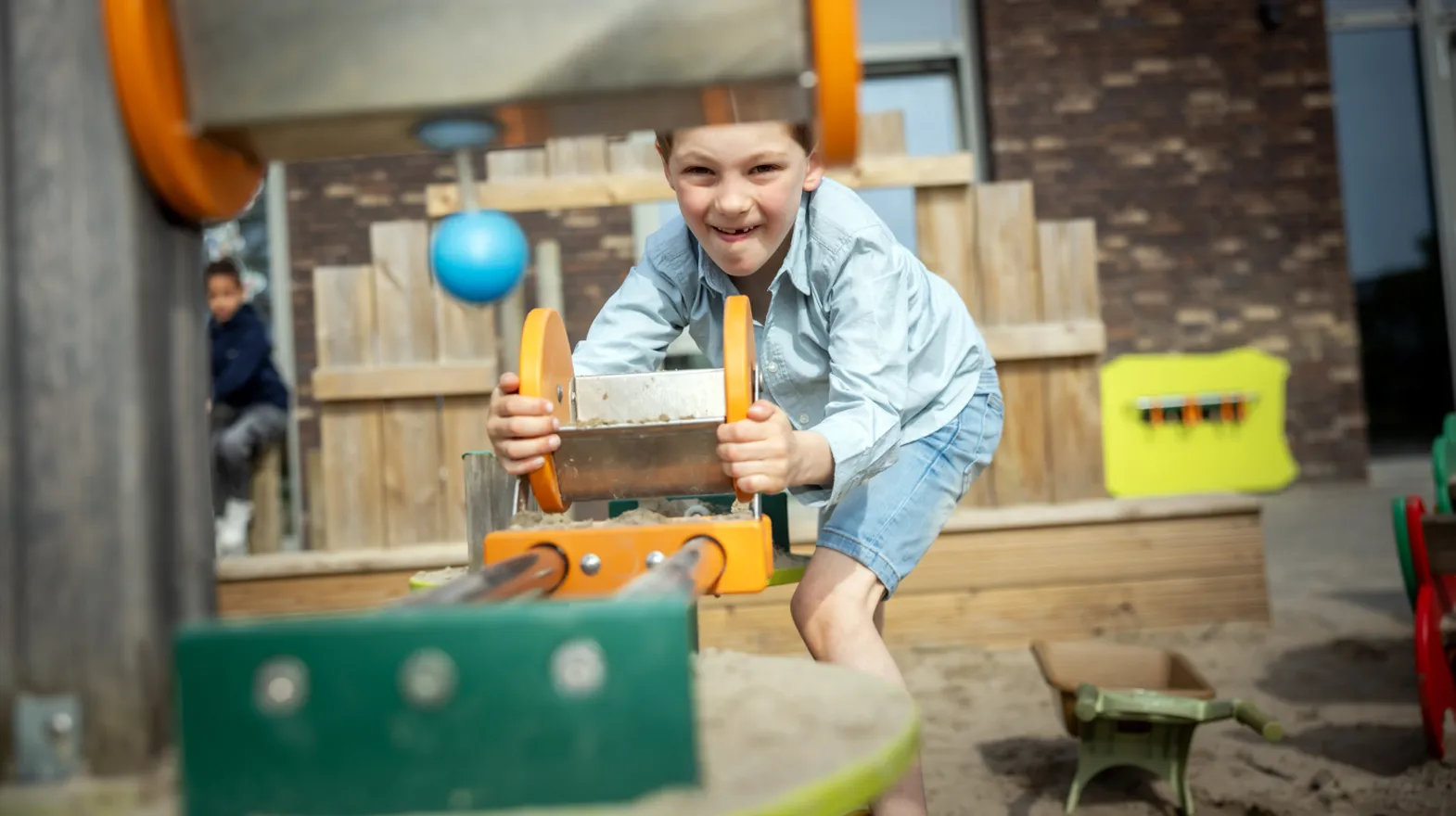 Kind speelt buiten met zand bij kinderopvang Kind&co ludens