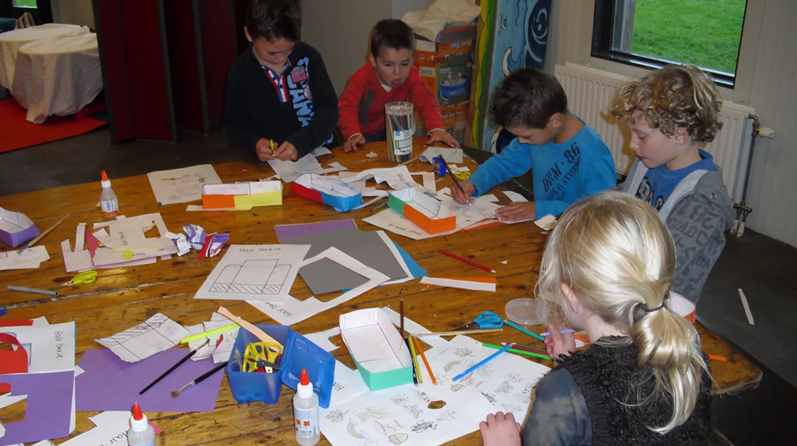 Kinderen knutselen samen aan tafel bij buitenschoolse opvang Gouddelvers, kinderopvang Kind&co ludens
