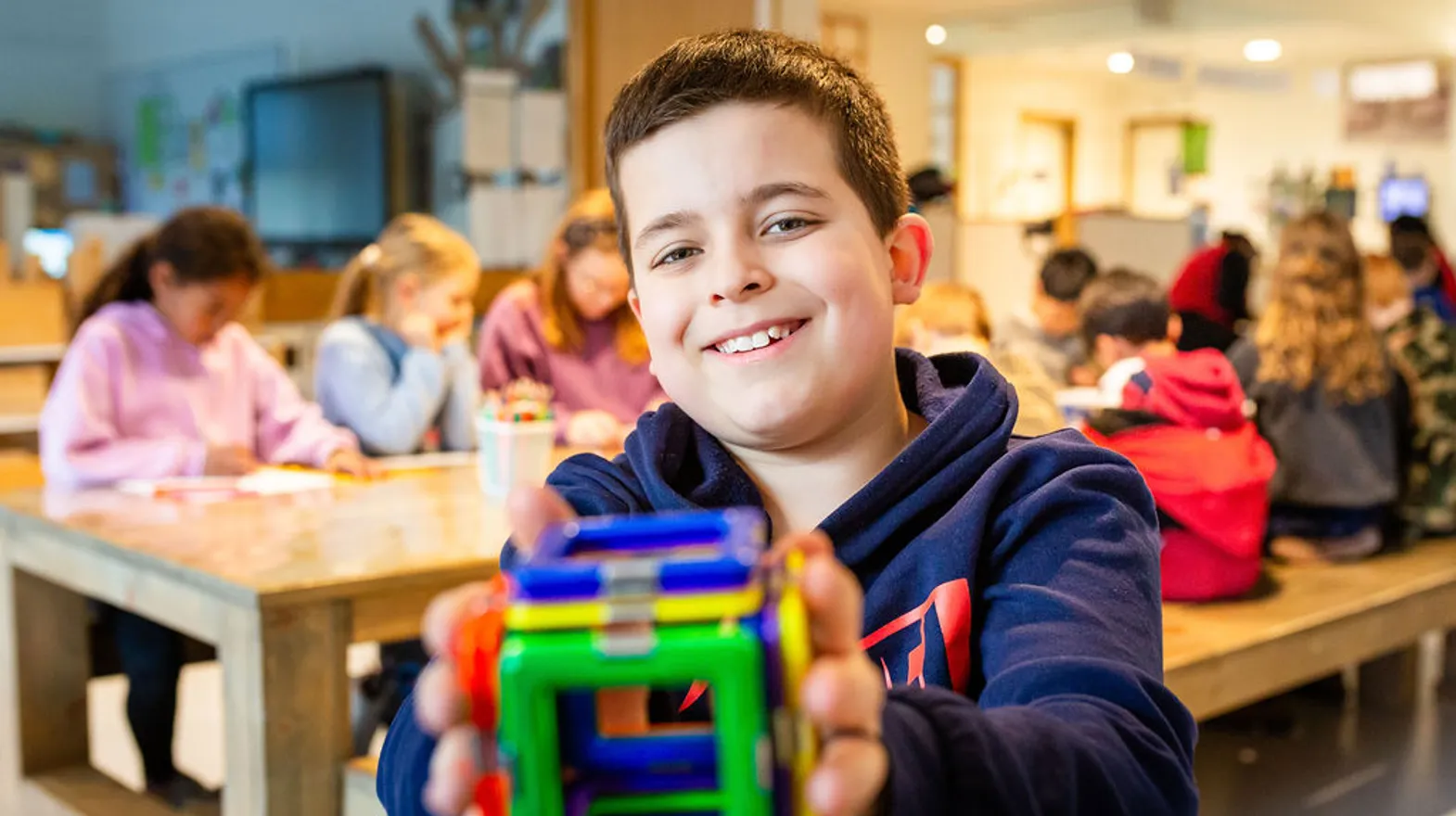 Kind laat blij zijn gemaakte magnetenkubus zien bij buitenschoolse opvang Grote Beer, kinderopvang Kind&co Ludens