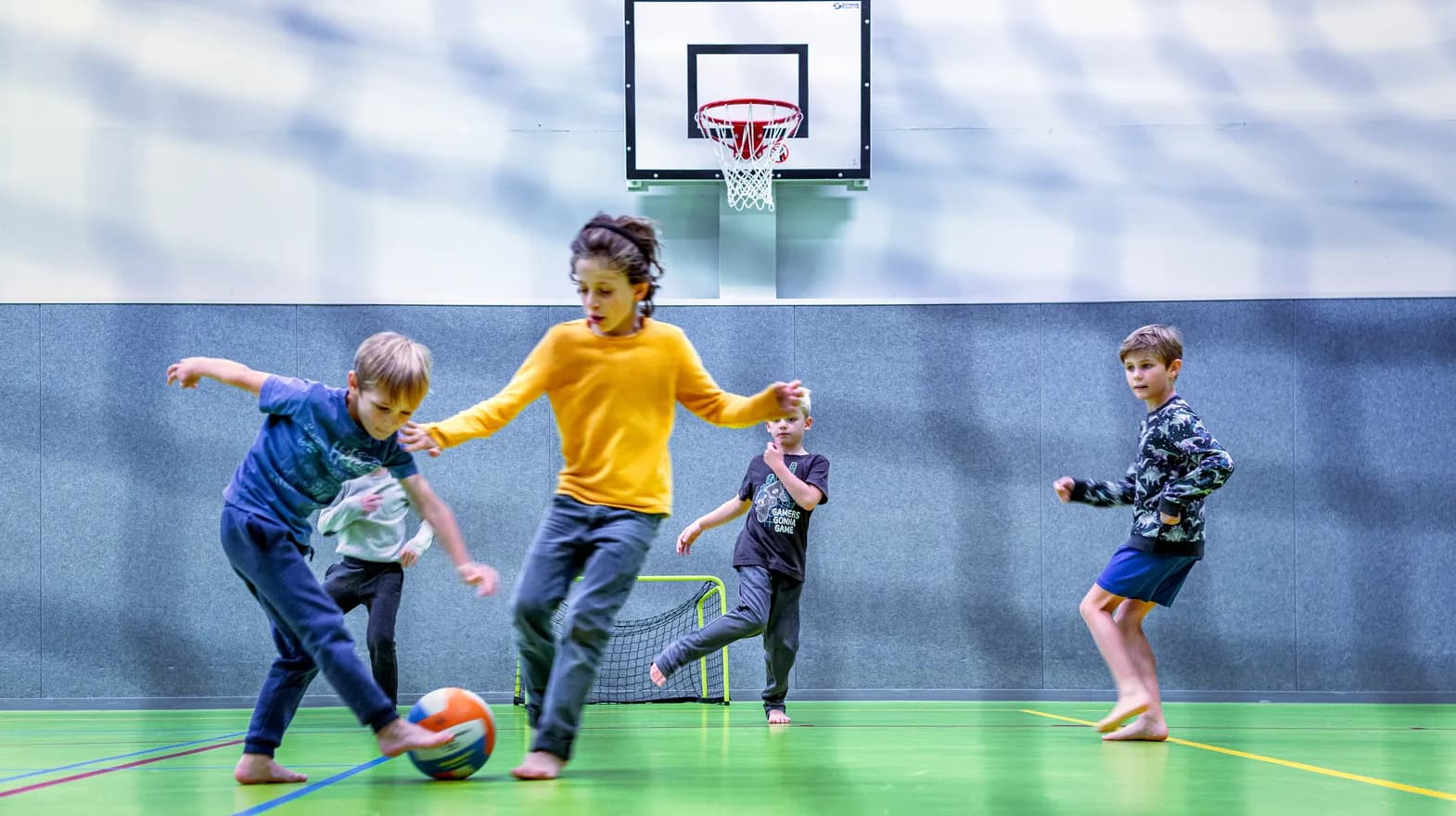 Kinderen van de BSO spelen samen voetbal in de gymzaal bij kinderopvang Kind&co ludens