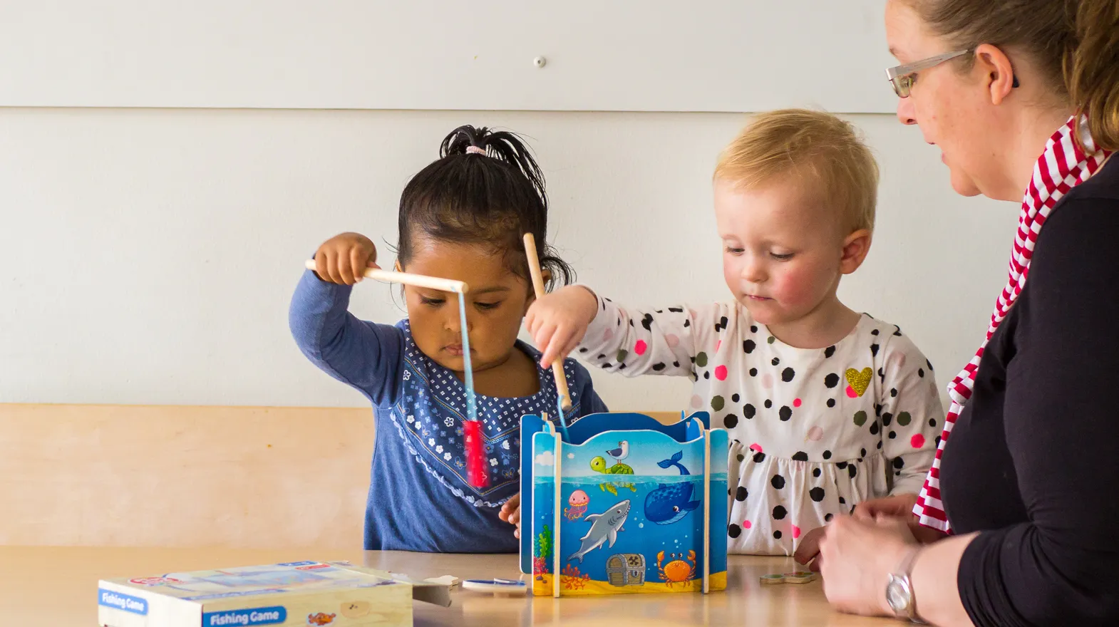 Kinderen spelen samen "Vissen" onder begeleiding van een pedagogisch medewerker bij kinderopvang Kind&co ludens