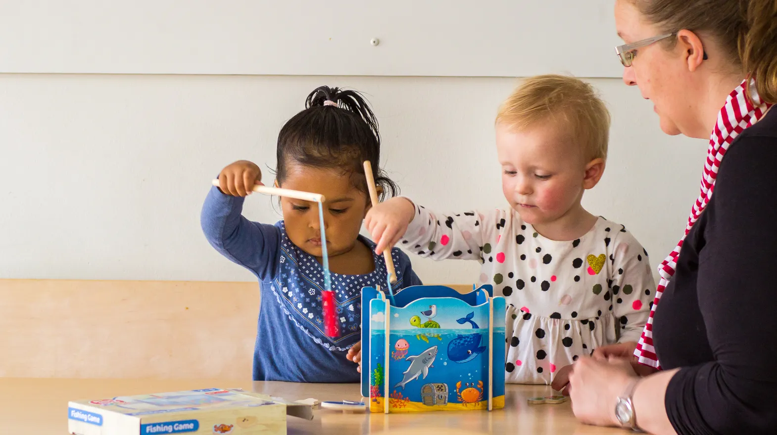 Kinderen spelen samen "Vissen" onder begeleiding van een pedagogisch medewerker bij kinderopvang Kind&co ludens