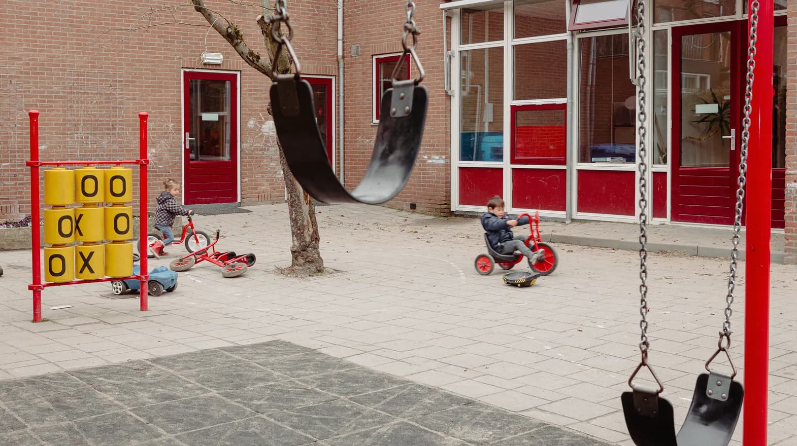 Kinderen fietsen buiten op het plein bij peuteropvang Kadodder, Kind&co ludens