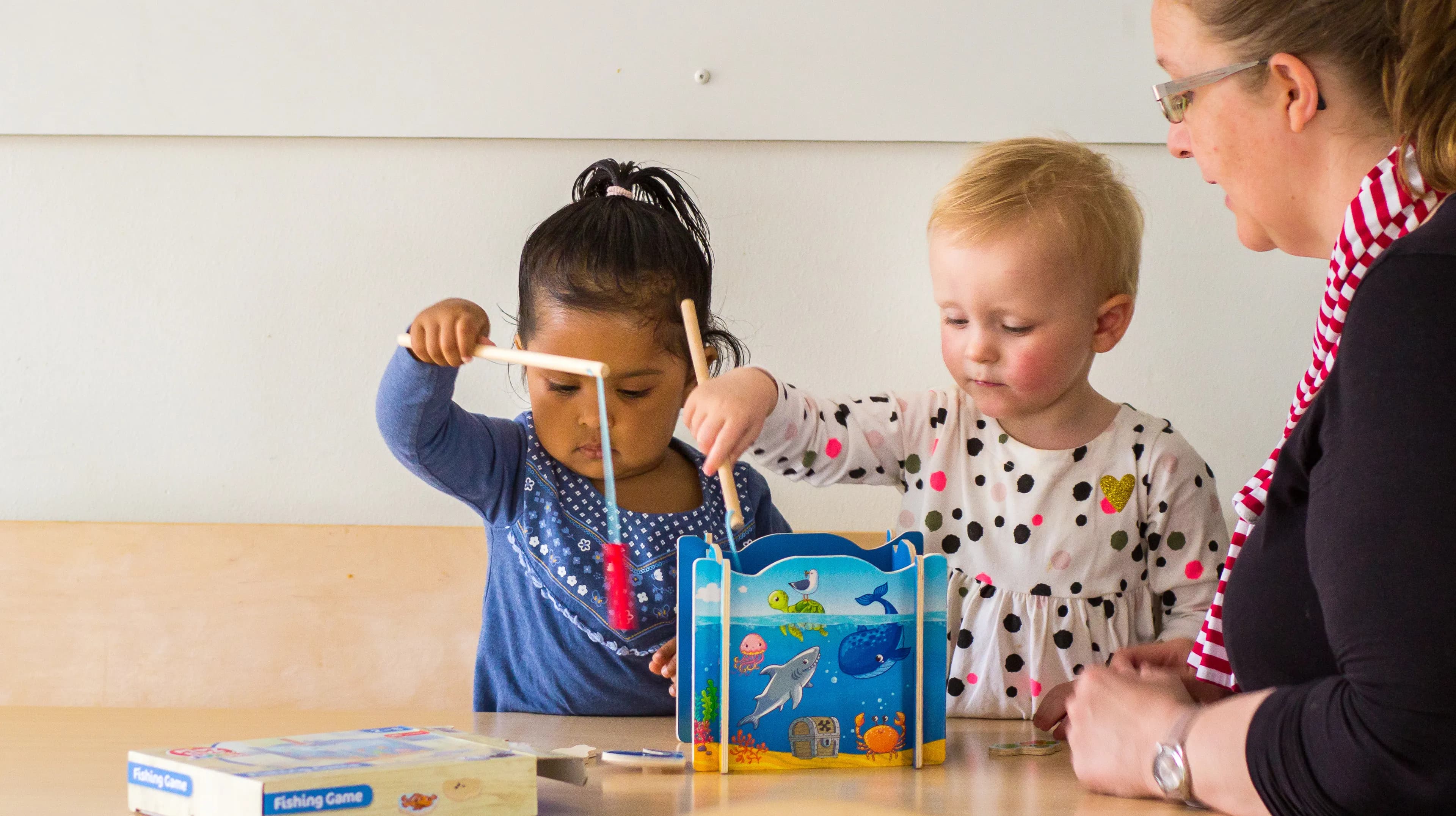 Kinderen spelen samen "Vissen" onder begeleiding van een pedagogisch medewerker bij kinderopvang Kind&co ludens