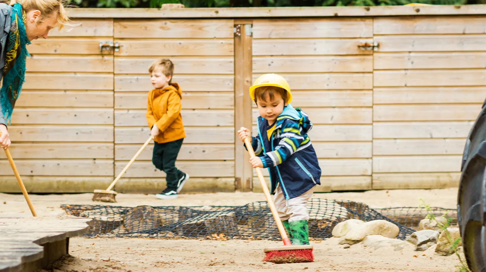Kinderen samen met de pedagogisch medewerker buiten aan het vegen bij kinderopvang Kind&co ludens