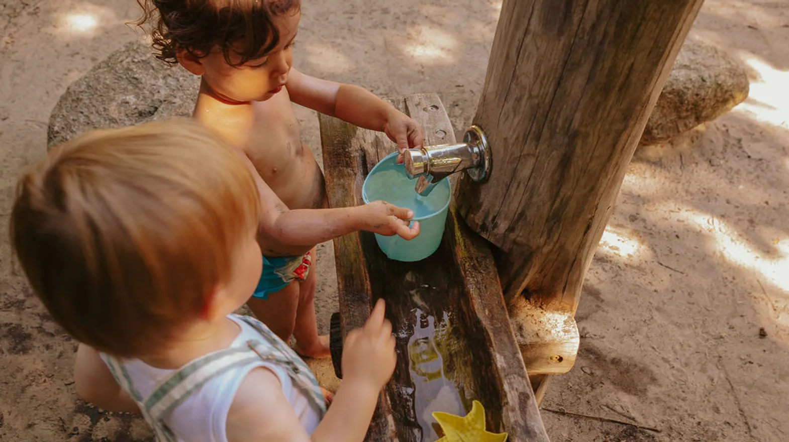 Kinderen spelen buiten met modder en water bij kinderopvang Kind&co ludens
