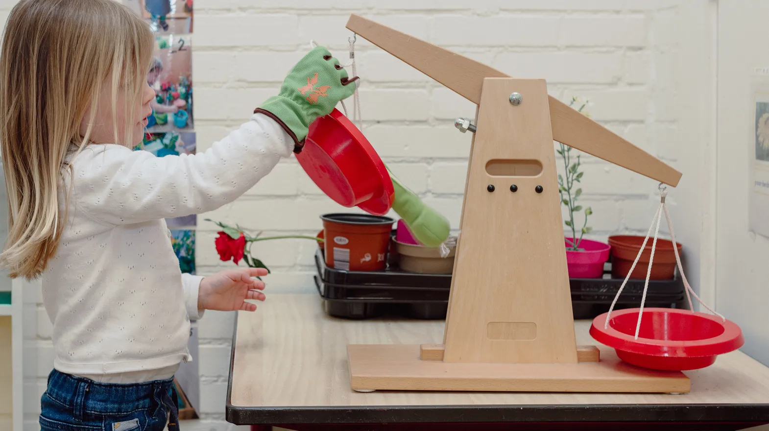 Een kind van de peutergroep speelt met een weegschaal bij kinderopvang Kind&co ludens