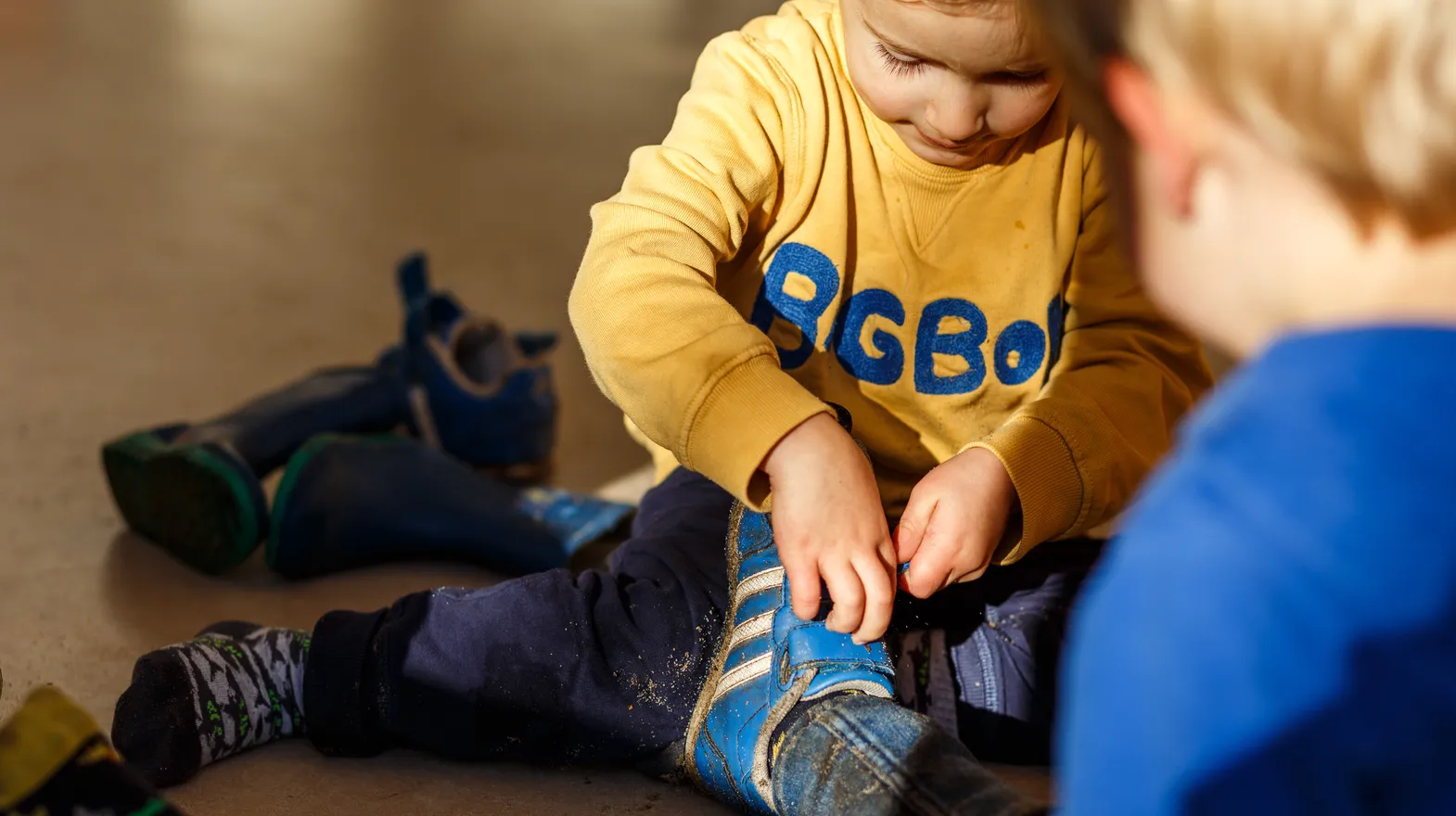 Kinderen doen samen hun schoenen uit bij kinderopvang Kind&co ludens