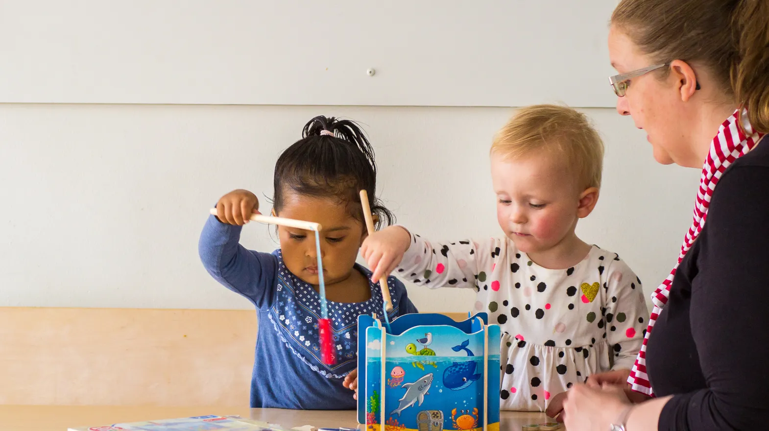 Kinderen spelen samen "Vissen" onder begeleiding van een pedagogisch medewerker bij kinderopvang Kind&co ludens