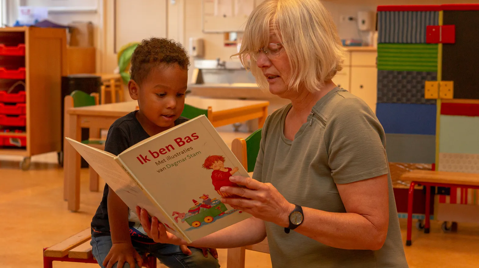 Pedagogisch medewerker leest een boek voor aan kind bij peuteropvang Het Margrietje, kinderopvang Kind&co ludens