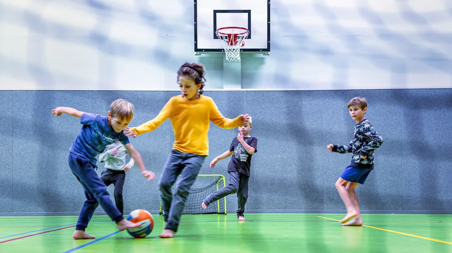 Kinderen van de BSO spelen samen voetbal in de gymzaal bij kinderopvang Kind&co ludens